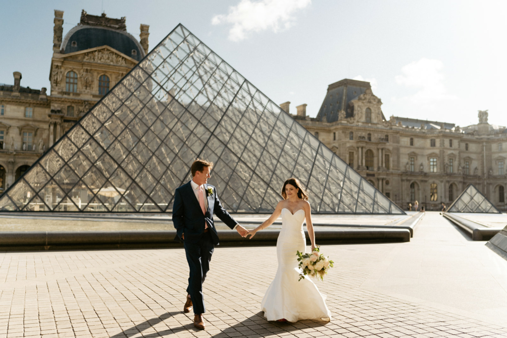 wedding couple at the louvre pyramid for their paris honeymoon tips