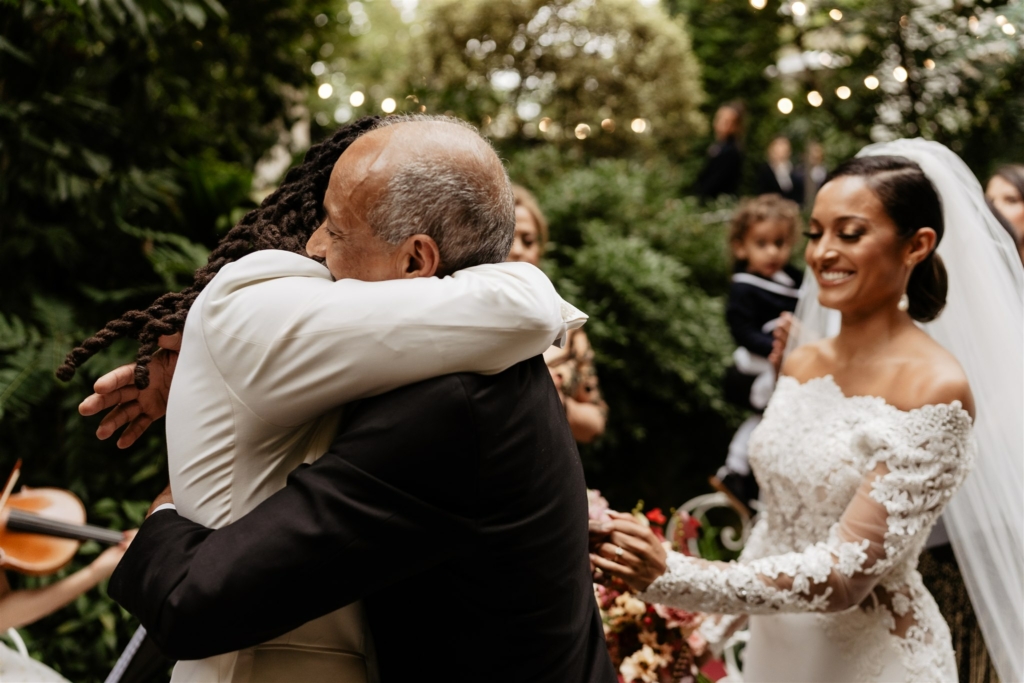 the father of the bride and the groom are hugging during the wedding ceremony taking place at the hotel particulier montmartre in Paris, ceremony is held by a paris officiant